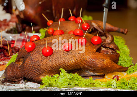 Dinde rôtie garnie de tomates décorées sur table Banque D'Images