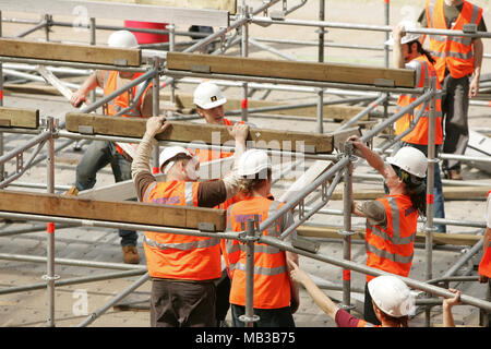 Un groupe de travailleurs de la construction d'une scène de concert à l'aide d'échafaudages temporaires habillés en vêtements de protection et un casque. Banque D'Images