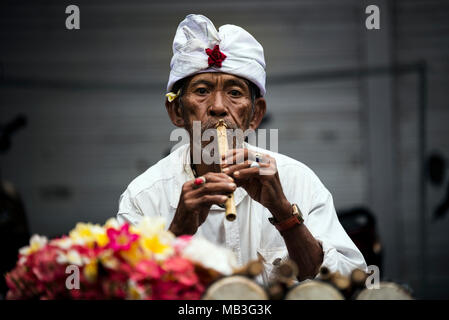 Bali, Indonésie - Juillet 9, 2017. 50s mâle balinais musicien de rue jouant un instrument local du vent et les vendre. Bali / Indonésie. Banque D'Images