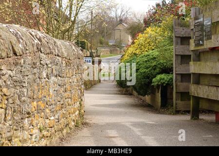 Anglais quaint village idyllique de marche dans l'Oxfordshire, UK avec mur en pierre, arbres et vue de route dans la distance Banque D'Images