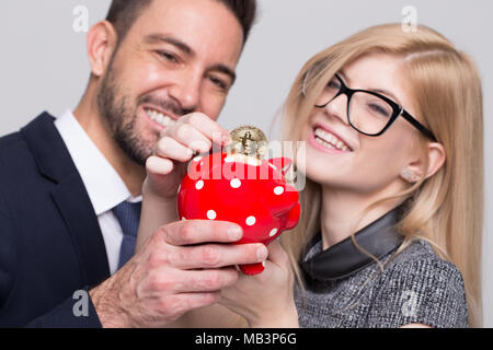 Young caucasian businessman and businesswoman enregistrer en bitcoin tirelire en pointillés rouges, conceptuel Banque D'Images