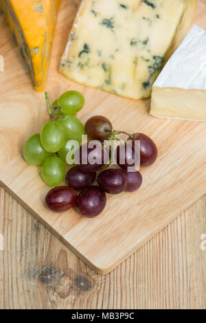 Vue aérienne de frais généraux d'une sélection de raisins rouges et verts avec un plateau de fromages en bois servant à bord lors d'une journée ensoleillée Banque D'Images