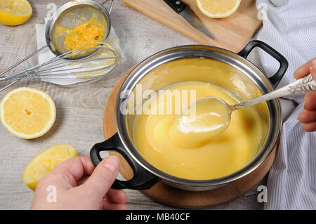 Kurde de citron fraîchement préparés - crème anglaise sur les jus de fruits dans une casserole, remuer avec une cuillère Banque D'Images