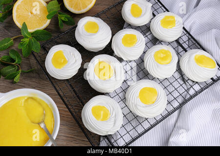 Remplissage d'un kurde de citron, un délicat, mini-dessert croustillant "Pavlova" sur le rack Banque D'Images