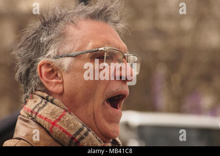 Un homme debout à Londres lors d'une journée froide enveloppée dans un foulard regardant les passants Banque D'Images