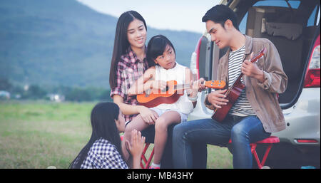 Happy little girl playing ukulele avec asian family dans la voiture pour profiter de la route et les vacances d'été Banque D'Images