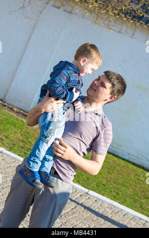 Père et son petit fils sont à la recherche à l'autre et souriant. Ils marchent dans le parc Banque D'Images