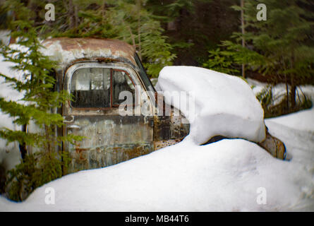 La cabine d'une vieille camionnette Dodge 1950, partiellement enterré dans la neige profonde, dans une zone boisée, derrière une grange, à Noxon, Montana, USA. Cette image a été sho Banque D'Images