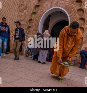 Man putting sur les chaussures après l'adoration à la mosquée de la koutoubia, Marrakech, Maroc Banque D'Images