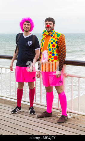 Bournemouth, Dorset, UK. 7 avril 2018. Météo France : après un début de journée humide le soleil essaie de sortir et en dépit d'être sur le côté froid de la tête aux visiteurs à la plage de Bournemouth pour profiter de la mer pendant les vacances de Pâques. Lumineux et colorés, un couple de mecs sur un enterrement Banque D'Images