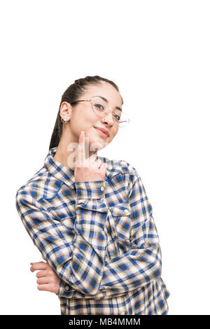 Alternative Smiling teen girl avec lunettes en chemise bleue à la caméra au doigt sur la joue Banque D'Images