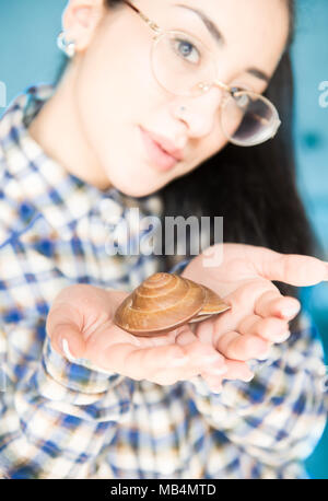Des mains avec sea shell à l'épargne et le don, fille de focus looking at camera, sea house concept Banque D'Images