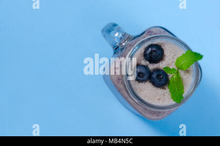 Frappé aux bleuets à la menthe en pot Mason verre avec de petits fruits et de menthe. Voir ci-dessus sur tableau bleu. Alimentation saine. Banque D'Images