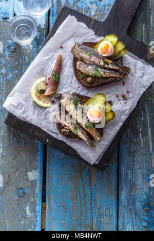 La vodka et un ensemble de sandwiches avec des anchois sur un fond de bois. Vue d'en haut. Copier l'espace. Banque D'Images
