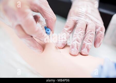 Médecin pratiquant l'insertion d'une ligne intraveineuse (IV) sur un mannequin de formation. Banque D'Images