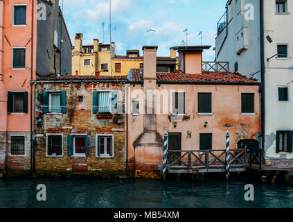 Façade de maison en briques anciennes moussus partiellement avec du vintage porte à petit canal à Venise, Italie Banque D'Images