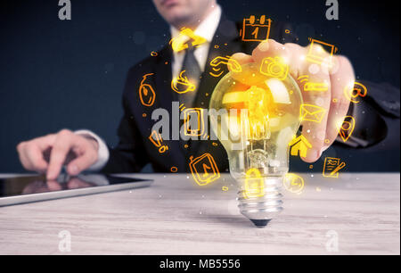 Un bureau commercial promouvoir ses idées de concept avec l'illustration des médias en ligne et les logos de l'appareil autour de l'ampoule en verre électrique. Banque D'Images