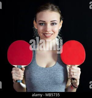 L'athlète tient dans ses mains deux chaussures de tennis de table sur un fond noir. Banque D'Images