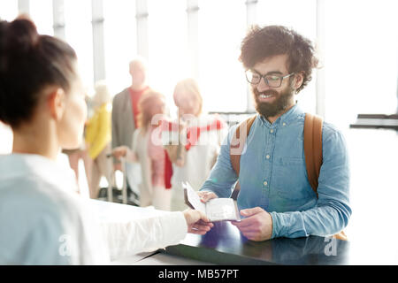 Jeune passager passeport donnant le check-in manager lors de l'enregistrement à l'aéroport avant le vol. Banque D'Images