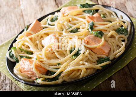 La cuisine italienne : spaghetti avec du saumon, du fromage à la crème et aux épinards close-up sur la plaque sur la table horizontale. Banque D'Images