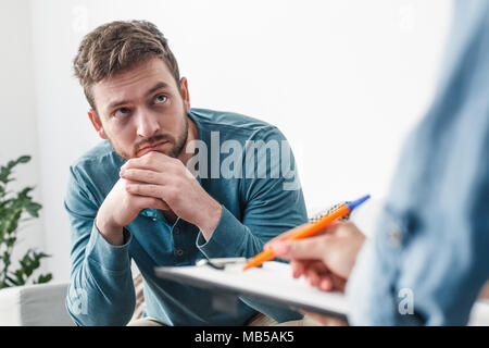 Homme avec des problèmes de toxicomanie psychologue concept assis sur un canapé à la prise de notes au médecin close-up Banque D'Images