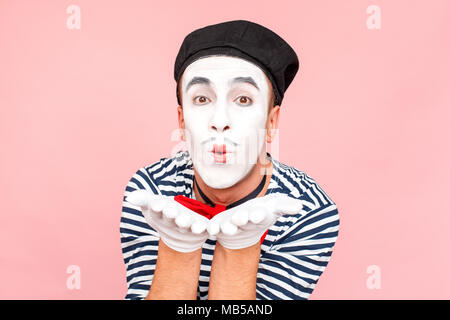 Portrait de l'homme en pull rayé, gants blancs de l'envoi de la baiser. Clown, artiste , mime. Fond rose, Studio shot Banque D'Images