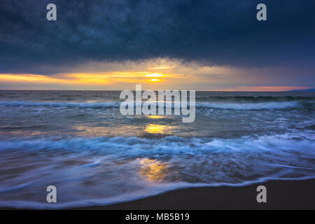 Une photographie de l'exposition des vagues lisses et soyeux sur le lavage de sable au coucher du soleil avec des nuages dans le ciel, Redondo Beach, Californie Banque D'Images