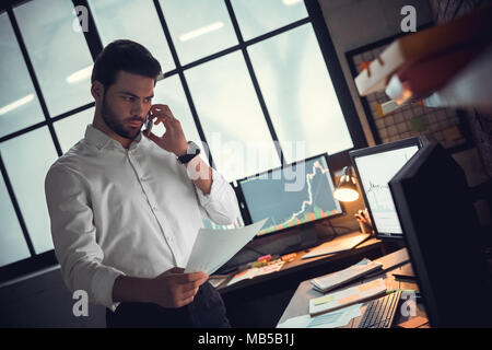 Jeune homme barbu trader at office debout près de la table document appelant réfléchis sérieux partenaire Banque D'Images
