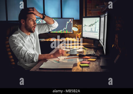 Jeune homme barbu trader at office sitting at table looking at computer choqué de toucher la tête déçu Banque D'Images