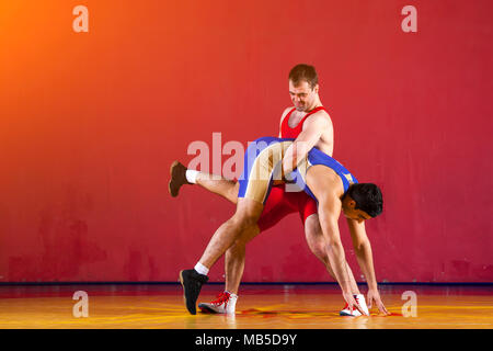 Deux lutteurs de lutte bleu collants sont wrestlng et faire une suplex wrestling wrestling jaune sur un tapis dans la salle de sport. Jeune homme faisant grap Banque D'Images