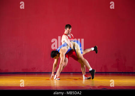 Deux lutteurs de lutte bleu collants sont wrestlng et faire une suplex wrestling wrestling jaune sur un tapis dans la salle de sport. Jeune homme faisant grap Banque D'Images