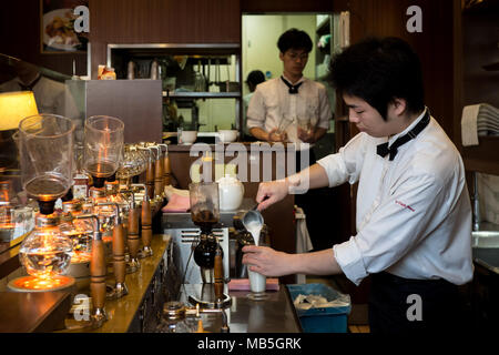 Café Barista avec un syphon cafetière et verser le lait à V Cafe Plaza à Osaka, Japon Banque D'Images