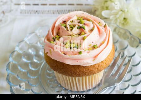 Dépoli Rose cup cake avec pistache nutrifer close up sur le verre plat à gâteau Banque D'Images