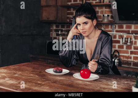 Belle jeune femme faisant choix entre Apple et donut, Close up sur la cuisine Banque D'Images