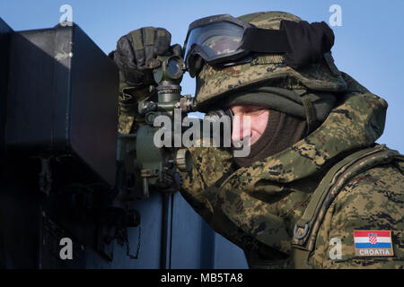 Un soldat de l'artillerie croate affecté à la batterie volcan vise son équipe's rocket artillery système tout en participant à l'exercice de groupe de combat Pologne à Puma une gamme près de la zone d'entraînement Bemowo Piskie, Pologne, le 22 février 2018. Ce soldat est une partie de l'unique groupe de combat multinationales, composé de États-Unis, Royaume-Uni, croate et soldats roumains qui servent avec la 15e Brigade mécanisée polonaise comme une force de dissuasion dans le nord-est de la Pologne à l'appui de l'OTAN vers l'amélioration de la présence. Banque D'Images