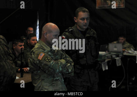 Le lieutenant-général Christopher Cavoli, United States Army Europe (USAREUR) Commandant, reçoit un rapport de renseignement sur les forces polonaises et des actifs qui participent à l'exercice Puma, un exercice pour tester l'interopérabilité entre le groupement tactique et ses quartiers généraux supérieurs, la 15e Brigade mécanisée de la Pologne, en Pologne, Orzysz, Février 22, 2018. La Pologne est un groupe de combat, l'unique groupe de combat multinationale, composée d'Américains, Britanniques, croate et soldats roumains qui servent avec la 15e Brigade mécanisée polonaise comme une force de dissuasion dans le nord-est de la Pologne à l'appui de l'OTAN vers l'amélioration de la présence. Banque D'Images