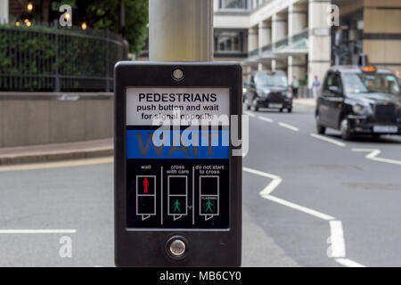 Une "Attente" signe des piétons à un passage pour piétons sur une route très fréquentée dans le centre de Londres, Angleterre Banque D'Images