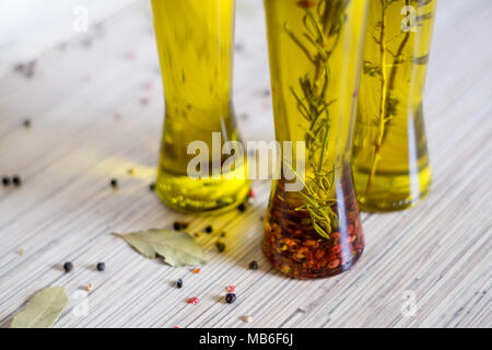 Graines de poivre colorés sur la table de cuisine et 3 bottes d'huile d'olive avec spieces, le romarin, le poivre, l'origan, le piment, la feuille de laurier en arrière-plan Banque D'Images