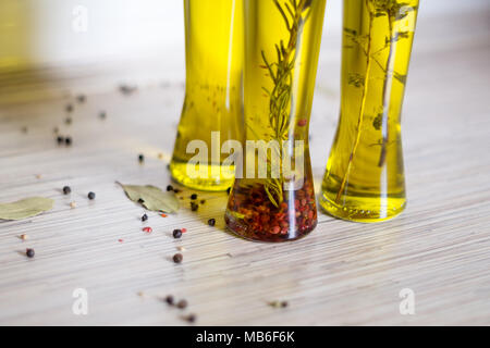 Graines de poivre colorés sur la table de cuisine et 3 bottes d'huile d'olive avec spieces, le romarin, le poivre, l'origan, le piment, la feuille de laurier en arrière-plan Banque D'Images