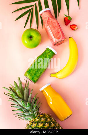 Les smoothies colorés dans des bouteilles avec fruits frais et sur fond rose, vue du dessus. Aliments biologiques naturelles Style. Banque D'Images