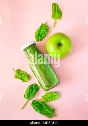 Smoothie vert bouteille colorée en rose sur l'arrière-plan, Vue de dessus. Aliments biologiques naturelles Style. Banque D'Images