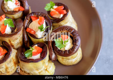 Rouleaux d'aubergine farcis de fromage décoré par paprika rouge et le persil. Banque D'Images