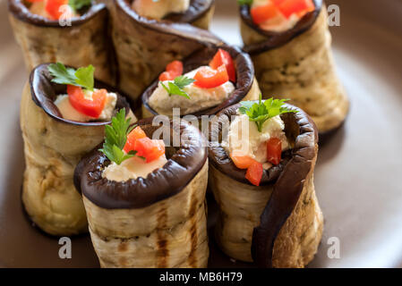 Rouleaux d'aubergine farcis de fromage décoré par paprika rouge et le persil. Banque D'Images