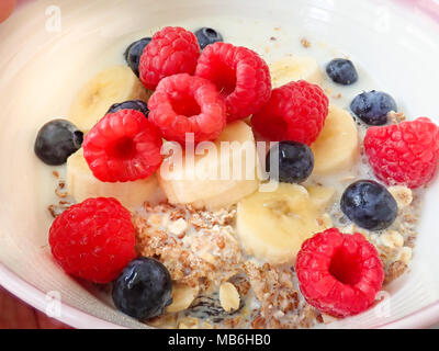 Petit-déjeuner bol de muesli avec des fruits. Framboises, bleuets et bananes avec du lait. Banque D'Images
