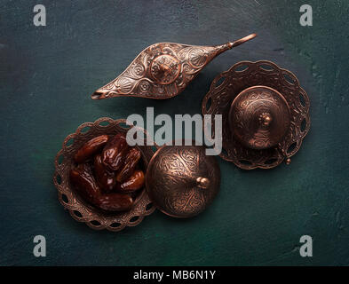 Plaque de bronze avec les dates et la lampe d'Aladdin vert foncé sur fond de bois. Mise à plat. Banque D'Images