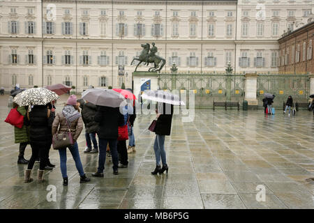 Les touristes avec parasols sur la Piazza Castello, Turin, Italie, avec le Palais Royal derrière. Banque D'Images