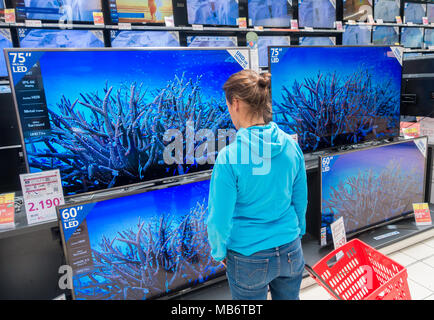 Femme à nouveau à 4k haute définition écrans de télévision en magasin électrique Banque D'Images