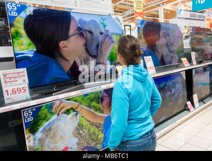 Femme à la recherche de nouveaux Samsung 4k haute définition télé des courbes store électrique Banque D'Images