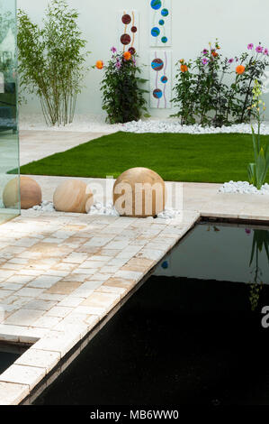 Contemporain et minimaliste, 'Breathe' show élégant jardin avec patio, mur blanc, étang et sphères de pierre - RHS Flower Show, Tatton Park, Angleterre, Royaume-Uni. Banque D'Images