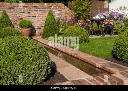 Dans l'eau, pelouses soignées, rigoles fort balls, mur et thé pour deux sous le soleil de son "un reflet de la vie" - show garden RHS Flower Show, Tatton Park, Angleterre, Royaume-Uni. Banque D'Images